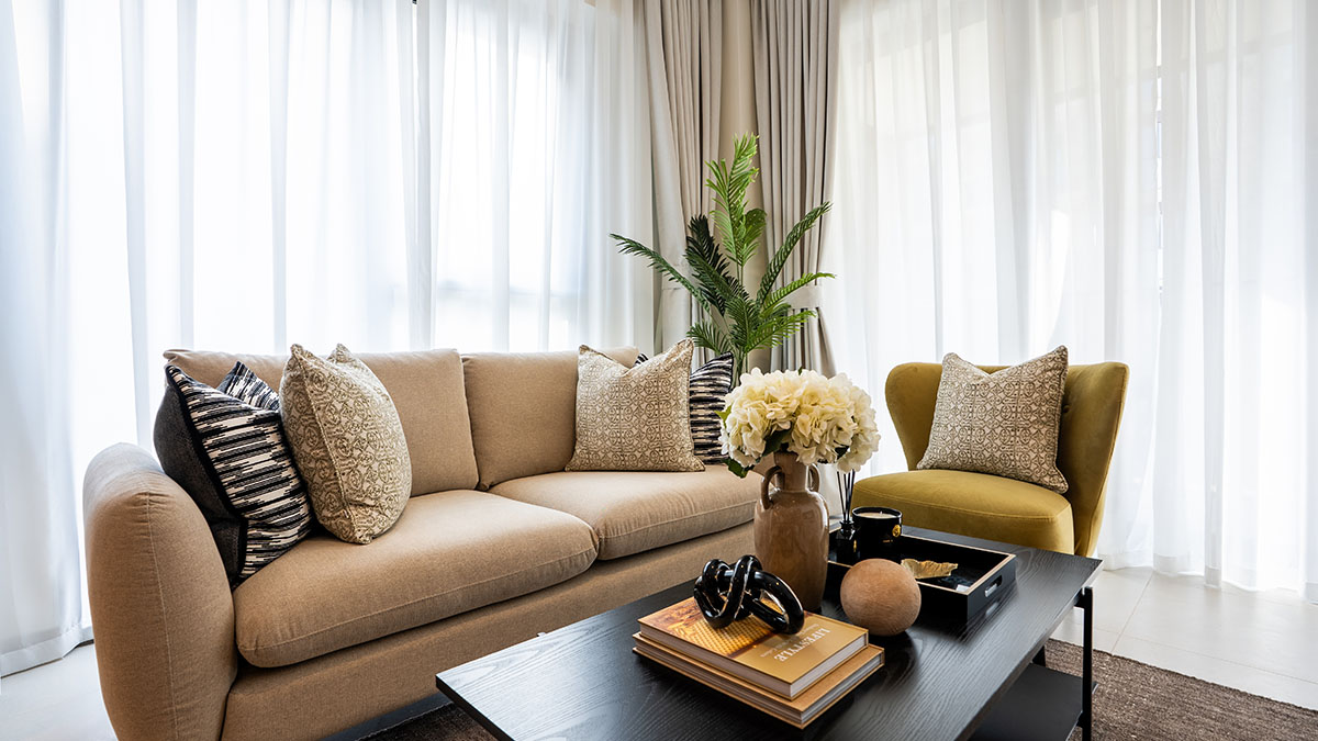 Bright contemporary living room with a beige sofa, patterned cushions, mustard accent chair and coordinated coffee table styling.