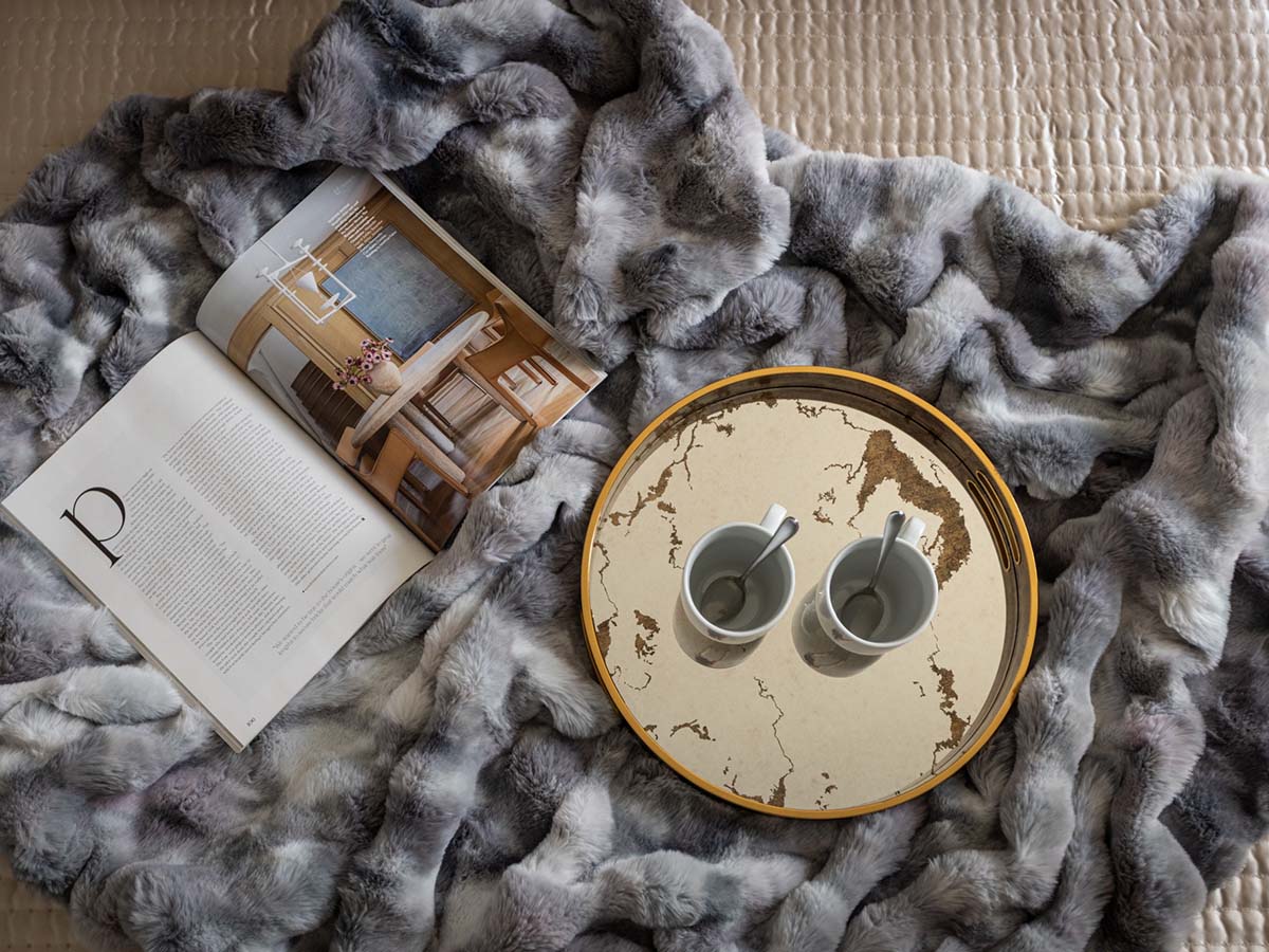 Cozy setup with a magazine and two cups on a tray over a soft blanket, reflecting modern interior design Dubai and premium furnishing services in Dubai